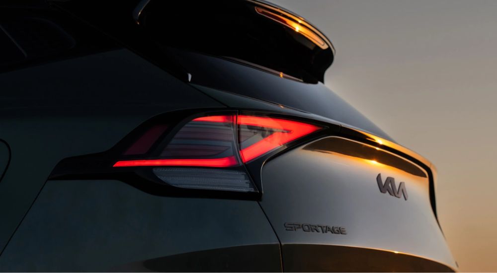 The rear end of a green 2025 Kia Sportage X-Pro Prestige at sunset.
