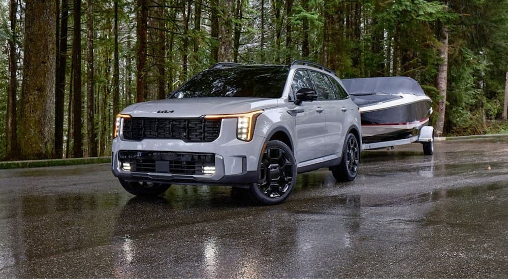 A white 2025 Kia Sorento for sale is towing a boat.