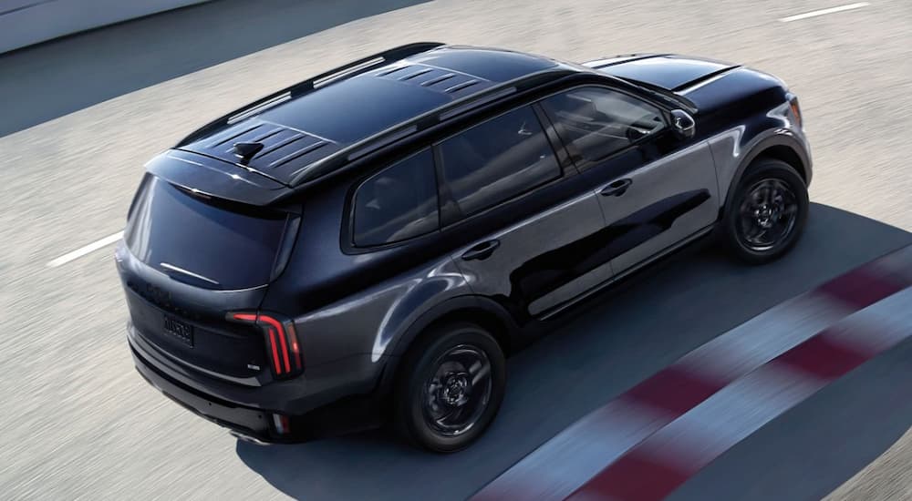 High angle view of a black 2026 Kia Telluride driving down a track.