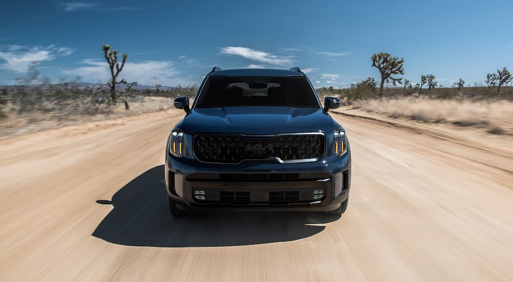 Black 2025 Kia Telluride driving down a desert road.