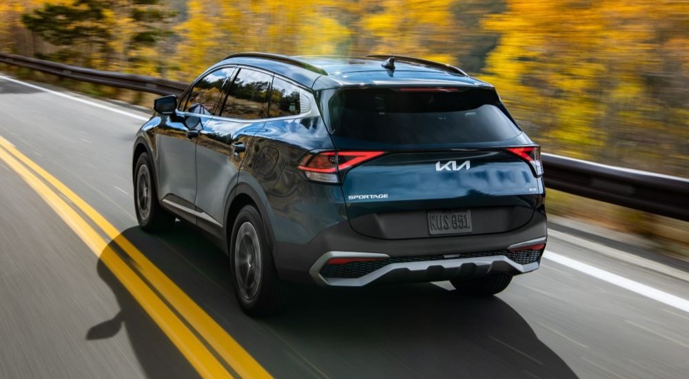 A blue 2023 Kia Sportage Hybrid driving down a highway