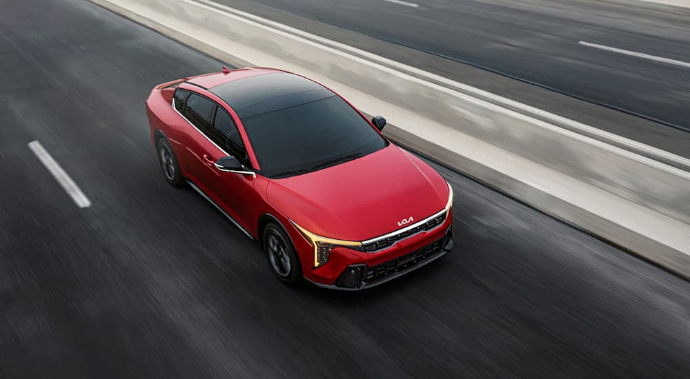 Red 2025 Kia K4 driving on a highway