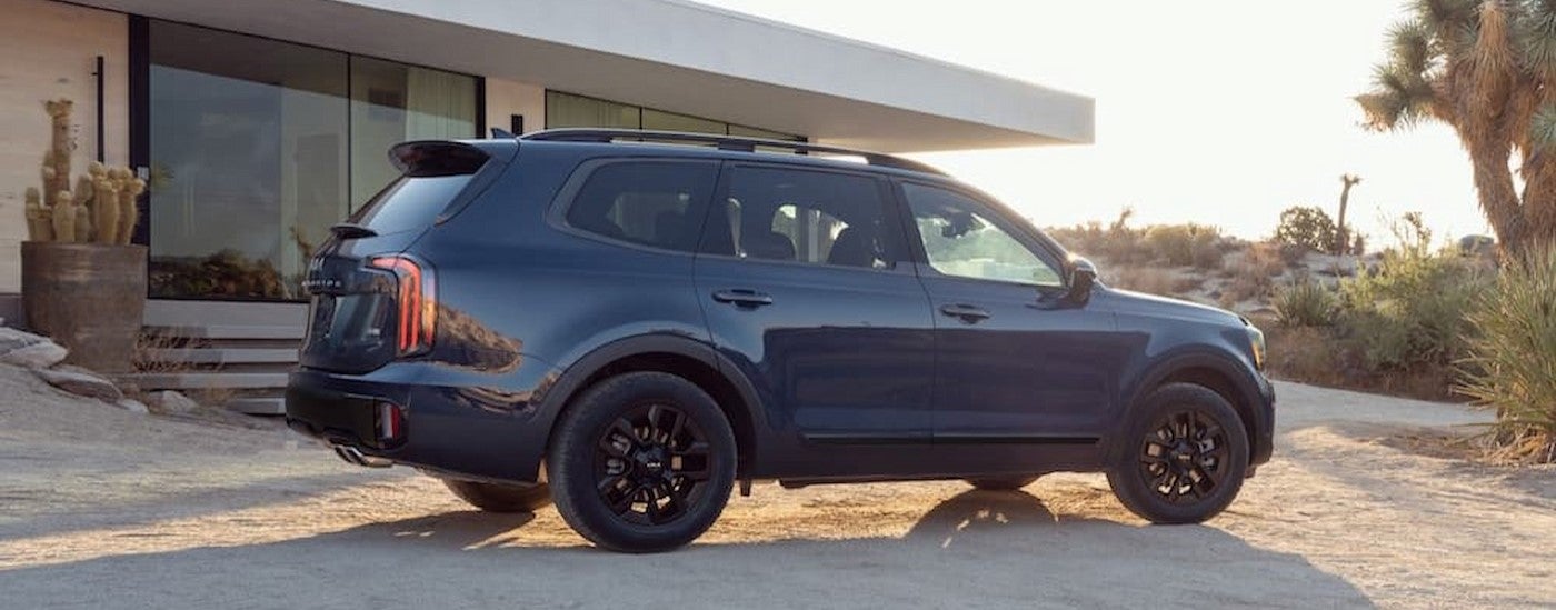 A gray 2024 Kia Telluride parked near a house.