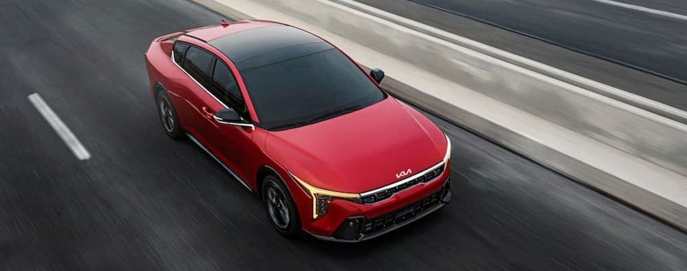A red 2025 Kia K4 EX drivin to a Kia dealer near Cudahy.