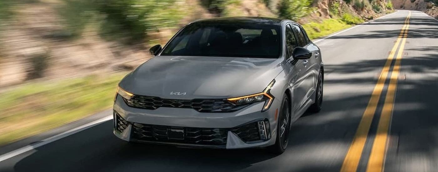 A gray 2025 Kia K5 GT driving on a highway.