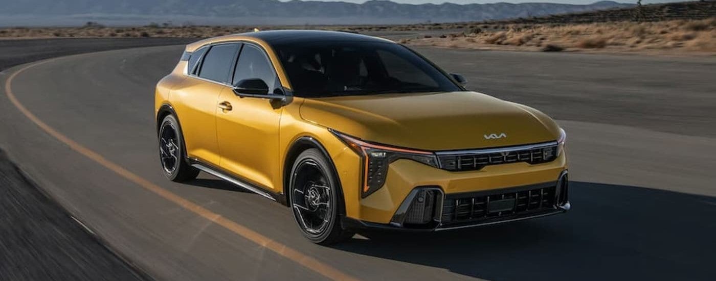 A gold 2026 Kia K4 Hatch driving to a Kia dealer near Oconomowoc.