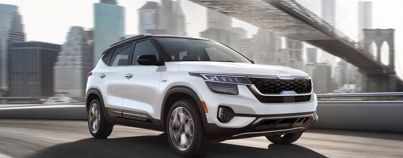 A white 2023 Kia Seltos is driving on a highway.