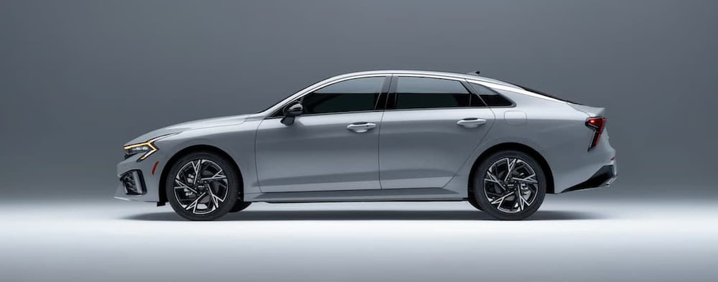 A silver 2025 Kia K5 parked in a showroom